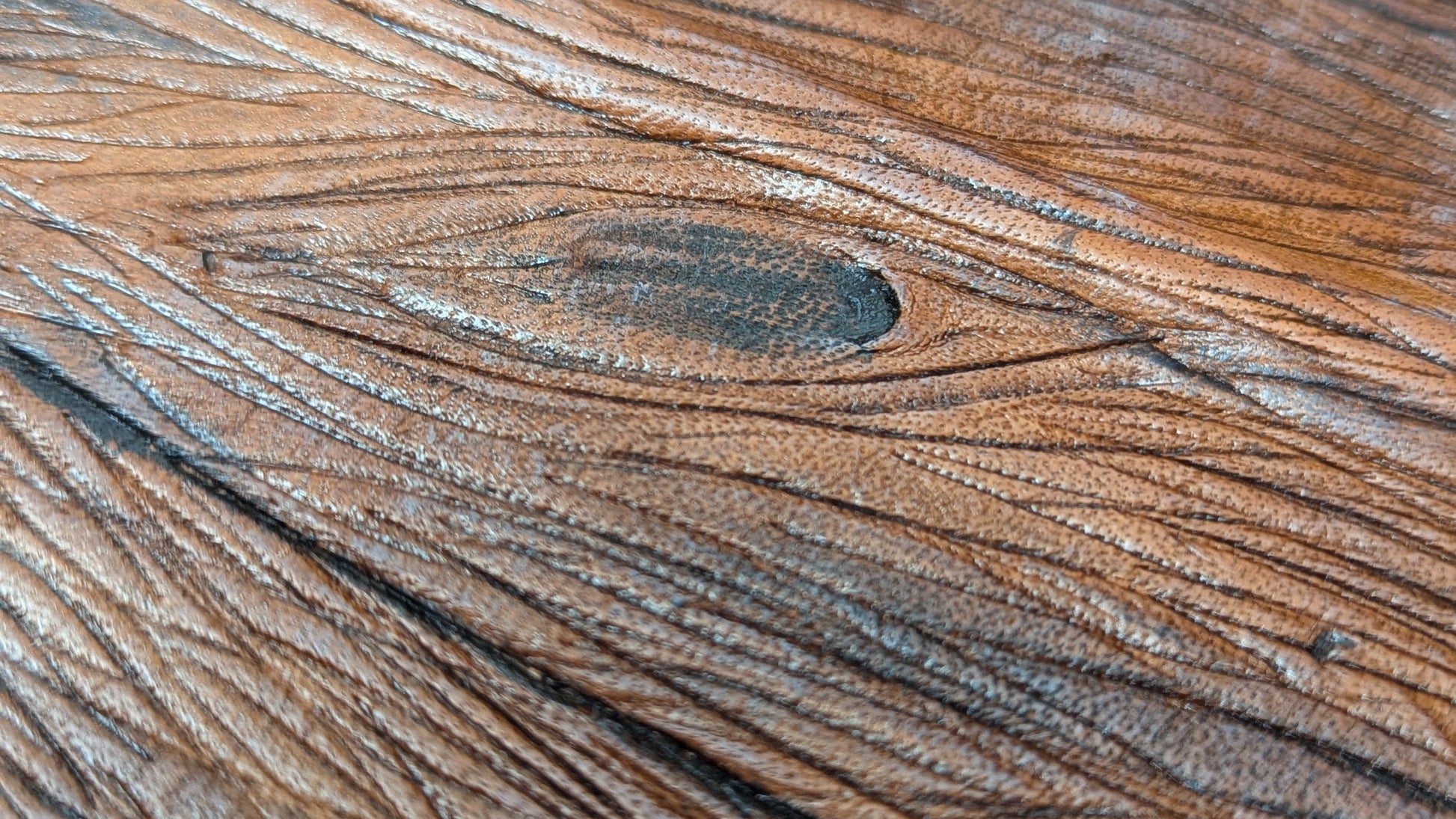Close-up of a faux wooden surface with visible grain and texture made on leather